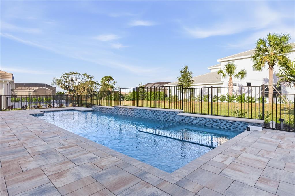 A swimming pool with a tiled water feature wall and three cascading fountains inside a screen — 8065 NEVIS RUN, BRADENTON, FL