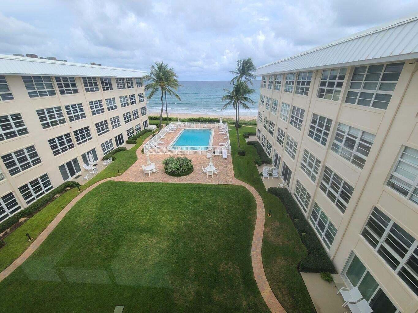 An elevated view of a courtyard with a swimming pool between two apartment buildings — 3851 N Ocean Boulevard # 409, Gulf Stream FL 33483, GULF STREAM, FL