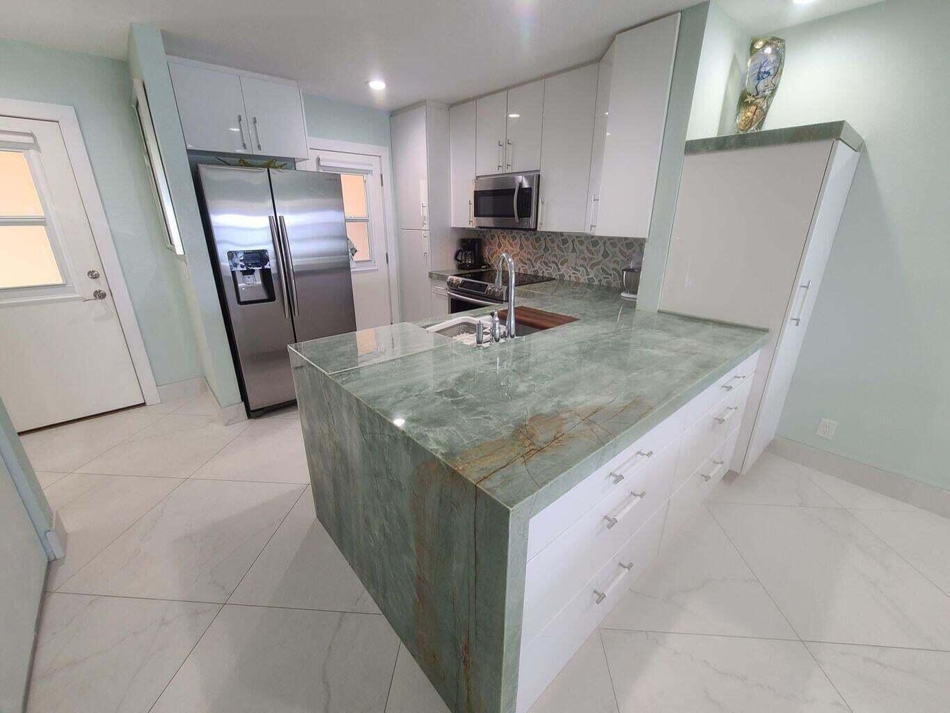 A kitchen features a green stone waterfall island, white cabinets, and stainless steel appliances — 3851 N Ocean Boulevard # 409, Gulf Stream FL 33483, GULF STREAM, FL
