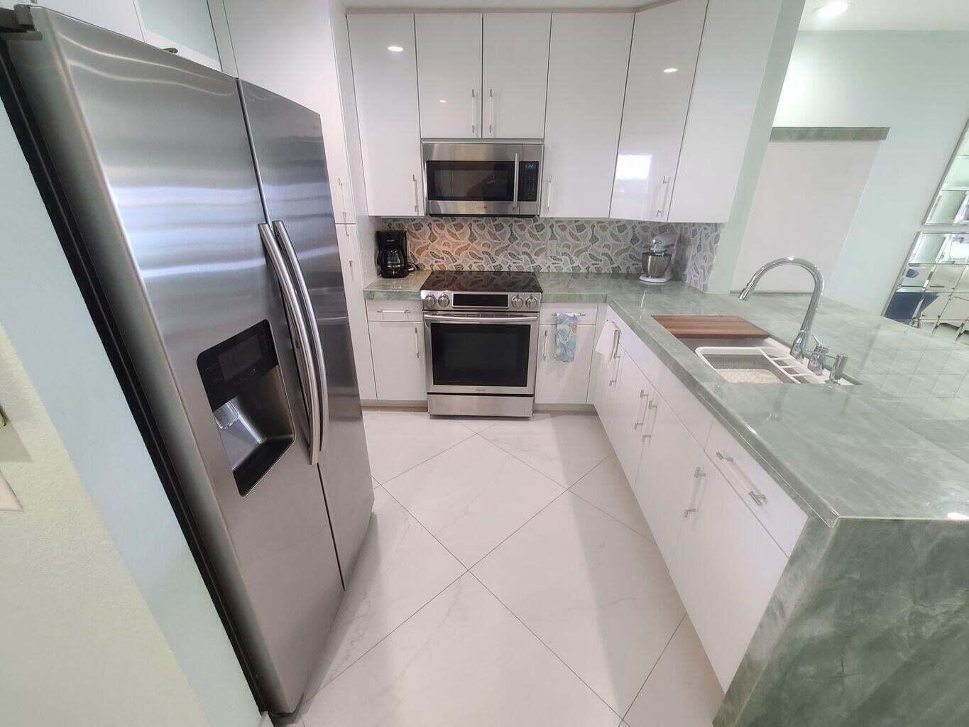 A modern kitchen features white cabinets, stainless steel appliances, and a green stone countertop — 3851 N Ocean Boulevard # 409, Gulf Stream FL 33483, GULF STREAM, FL