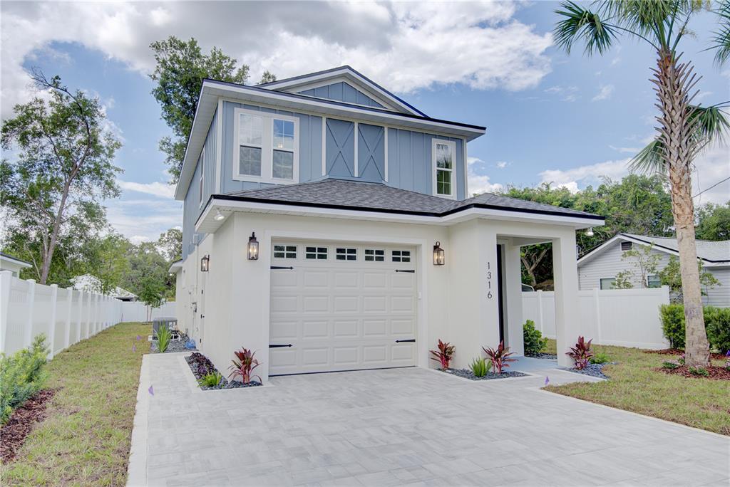 A two-story house with blue siding, a white stucco garage, and a paved driveway — 1316 E 9TH AVENUE, MOUNT DORA, FL