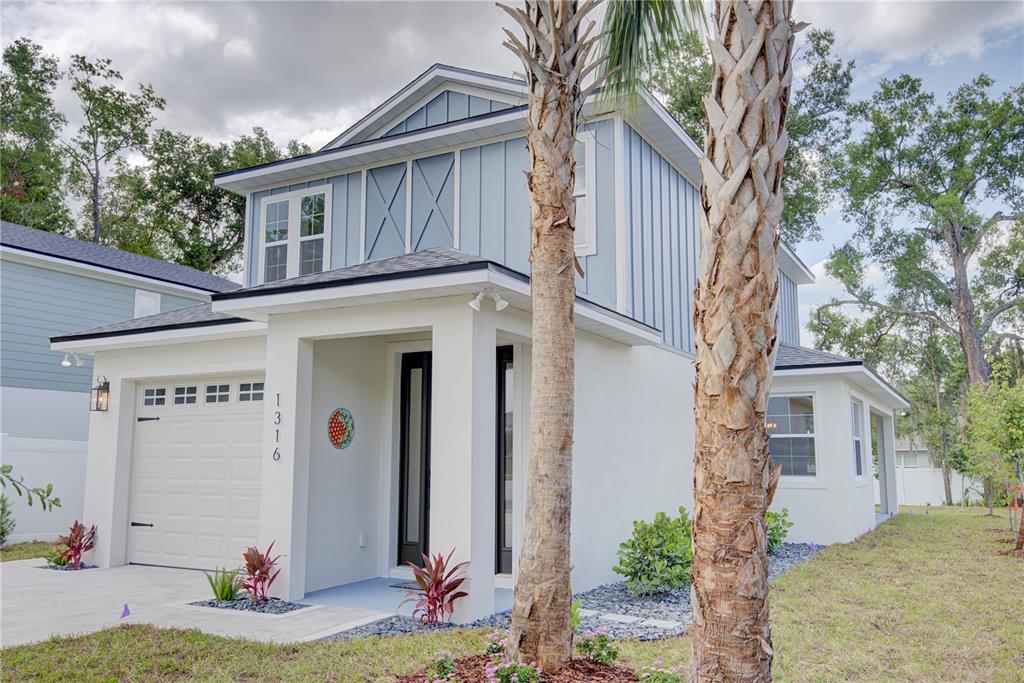 A two-story house with blue vertical siding, a white stucco base, and a front garage — 1316 E 9TH AVENUE, MOUNT DORA, FL