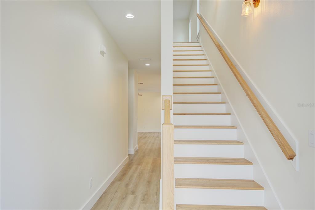 A staircase with light wood treads and white risers sits beside a hallway — 1316 E 9TH AVENUE, MOUNT DORA, FL