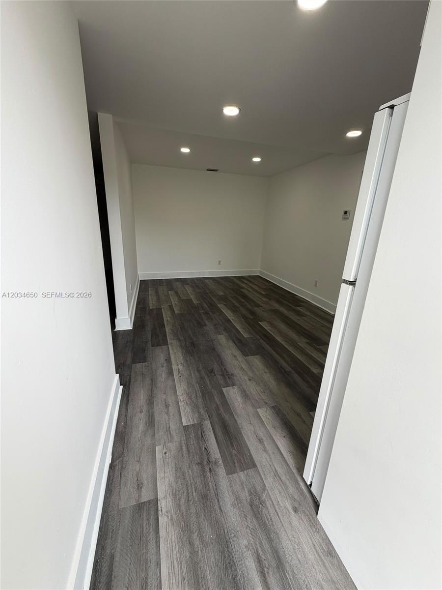 An empty room features white walls, recessed lighting, and dark wood-look laminate flooring — 2025 NW 72nd St # 2, Miami FL 33147, MIAMI, FL