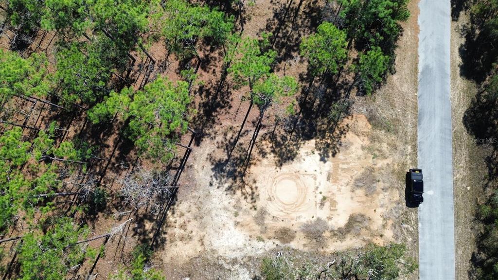 An aerial view shows a cleared sandy lot next to a paved road and trees — 24491 NW HEMLOCK AVENUE, DUNNELLON, FL