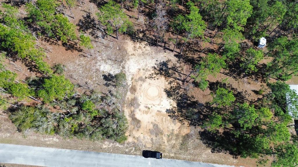 An aerial view shows a cleared sandy lot surrounded by trees next to a road — 24491 NW HEMLOCK AVENUE, DUNNELLON, FL
