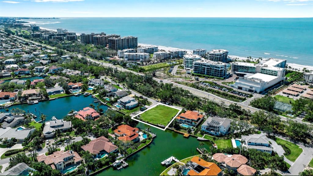 An aerial view shows a vacant waterfront lot surrounded by residential homes and coastal buildings — 1600 HARBOR SOUND DRIVE, LONGBOAT KEY, FL