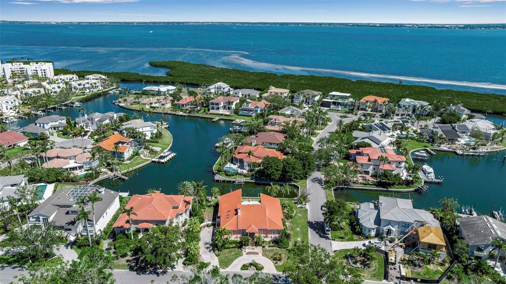 An aerial view shows waterfront homes with tiled roofs situated along canals near the ocean — 1600 HARBOR SOUND DRIVE, LONGBOAT KEY, FL