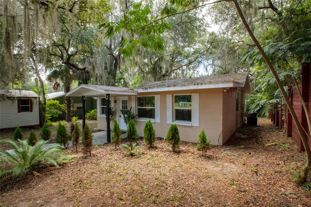 A single-story tan house with a small front porch sits among trees and landscaping — 111 2ND STREET, MELROSE, FL