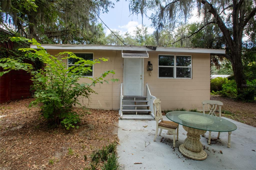A small, tan, single-story house with a white door, stairs, and a patio table — 111 2ND STREET, MELROSE, FL