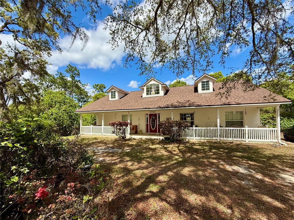A one-story house with a wrap-around porch and three dormer windows under a shingled roof — 41722 POINCIANA STREET, EUSTIS, FL