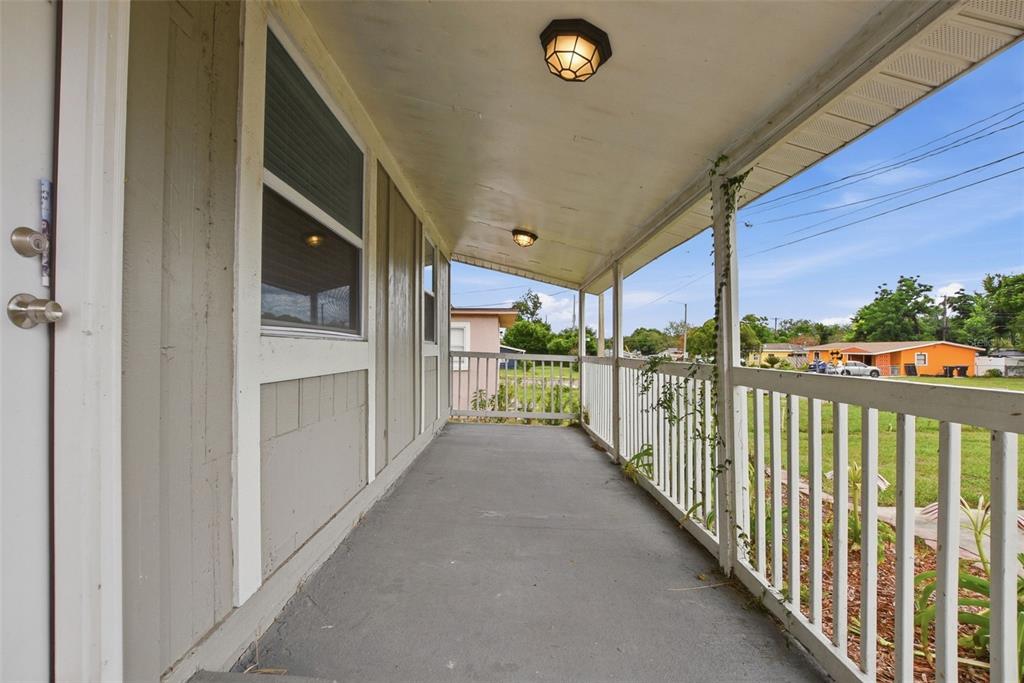 A covered porch with a concrete floor, white railings, and two ceiling lights — 6033 W AMELIA STREET, ORLANDO, FL
