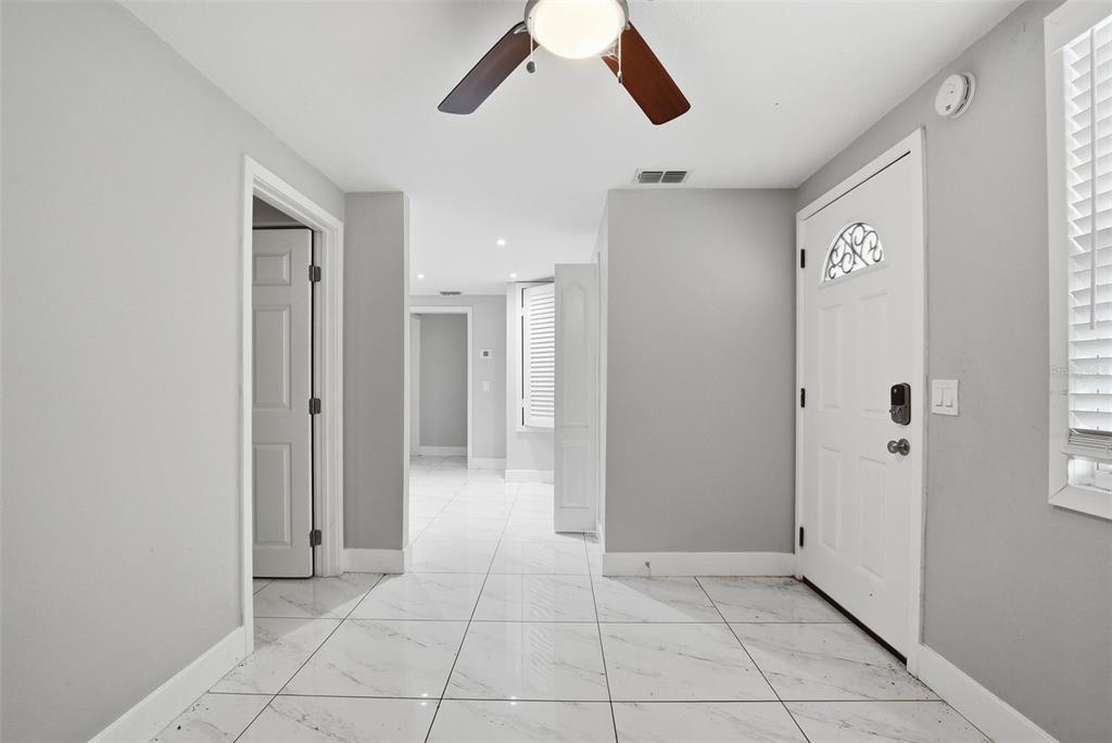 An entryway features white marble-look tile flooring, light gray walls, and a ceiling fan — 6033 W AMELIA STREET, ORLANDO, FL