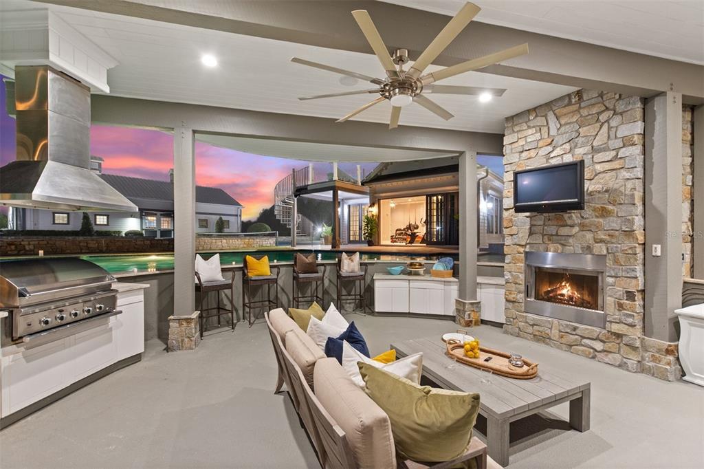A covered outdoor patio features a stone fireplace, built-in grill, seating area, and swimming pool — 3018 KINGFISHER POINT, CHULUOTA, FL
