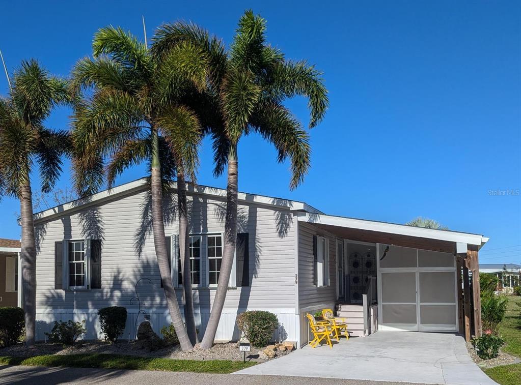 A single-story manufactured home with light siding, a carport, and palm trees in the front — 2100 KINGS HWY UNIT 279, PORT CHARLOTTE, FL