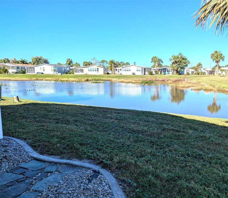 A view of a pond with houses in the background and a stone patio foreground — 2100 KINGS HWY UNIT 279, PORT CHARLOTTE, FL