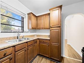 A kitchen features wood cabinets, granite countertops, a stainless steel sink, and light flooring — 1311 N 19th Ave # 1, Hollywood FL 33020, HOLLYWOOD, FL
