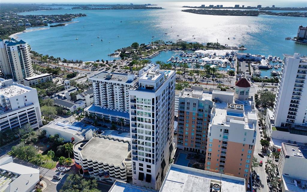 An aerial view shows a high-rise building surrounded by other structures, a marina, and water — 33 S PALM AVENUE UNIT 1501, SARASOTA, FL