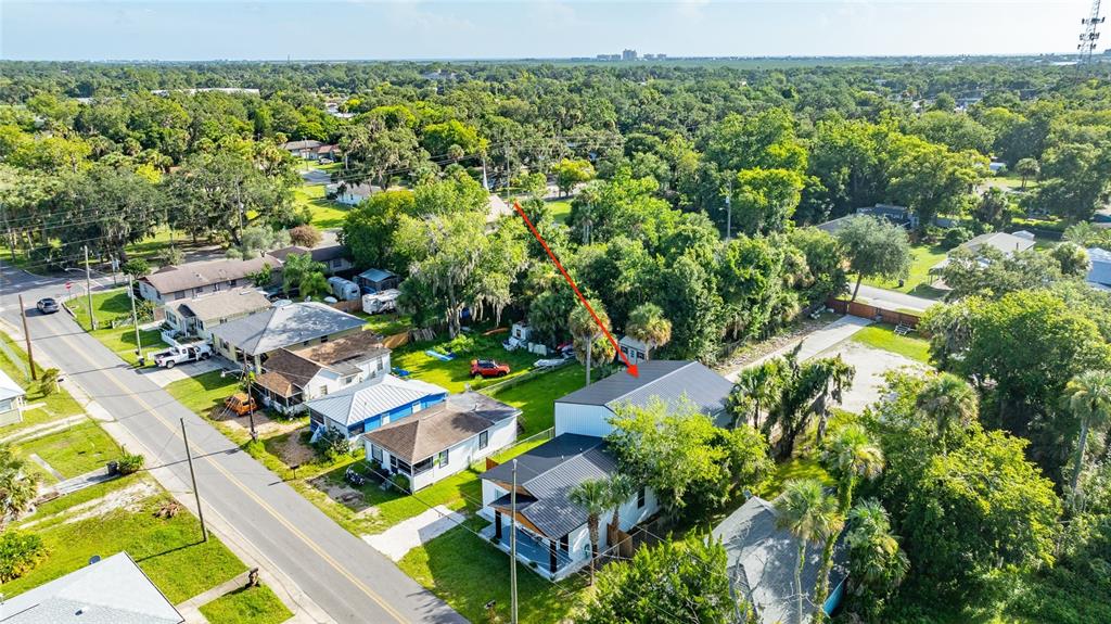 An aerial view shows a residential neighborhood with several houses and a red arrow pointing to a roof — 334 SHELDON STREET, NEW SMYRNA BEACH, FL