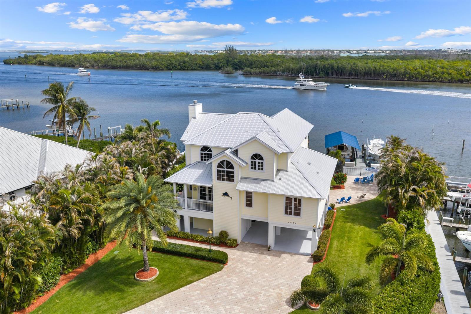 An aerial view shows a yellow, multi-story waterfront house with a metal roof and dock — 5675 SE Orange Street, Stuart FL 34997, STUART, FL