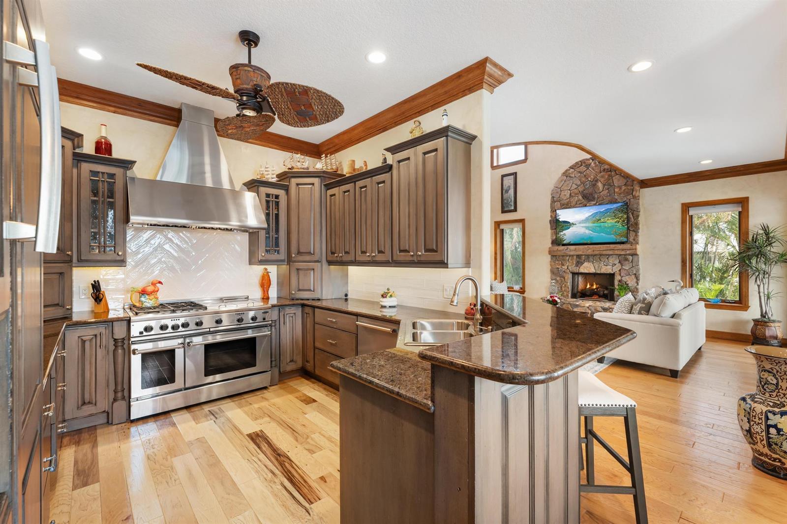 A kitchen with dark wood cabinets, granite countertops, and stainless steel appliances opens to a living room — 5675 SE Orange Street, Stuart FL 34997, STUART, FL