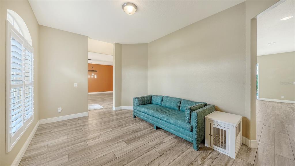 A living room features light-colored walls, wood-look tile flooring, a teal sofa, and a white crate — 116 NEW BRITON COURT, BRADENTON, FL