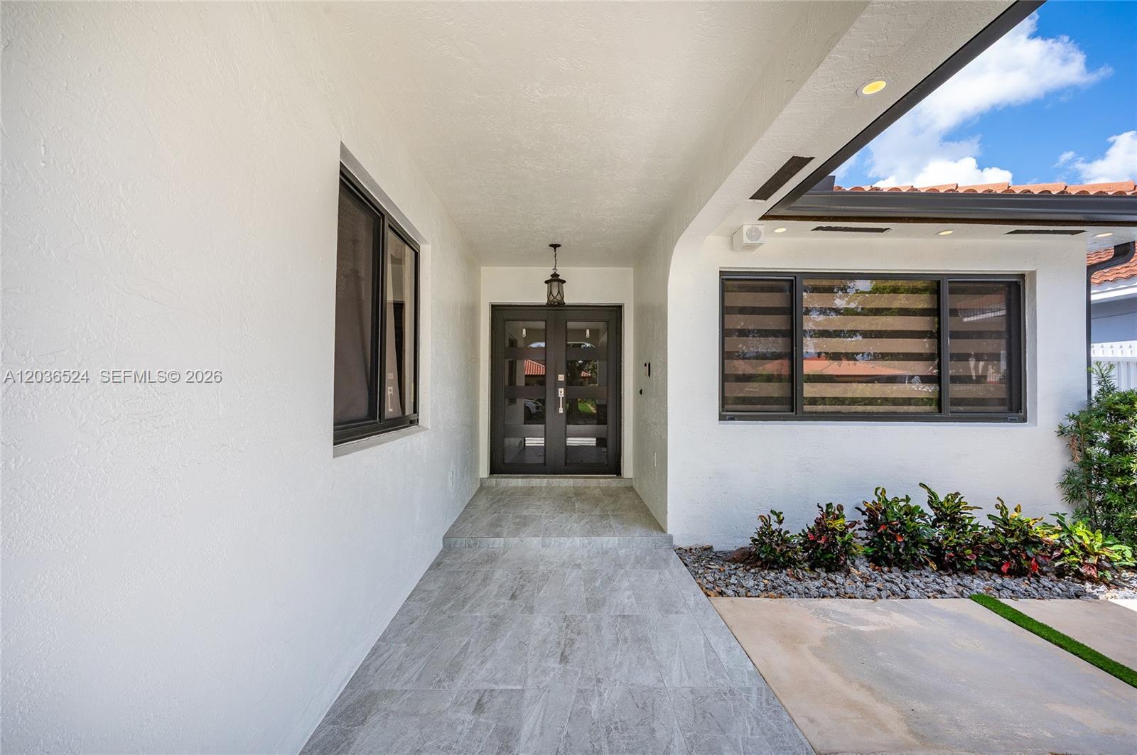 A covered entryway features a tiled floor, double glass doors, and dark-framed windows — 8724 NW 149th Ter, Miami Lakes FL 33018, MIAMI LAKES, FL