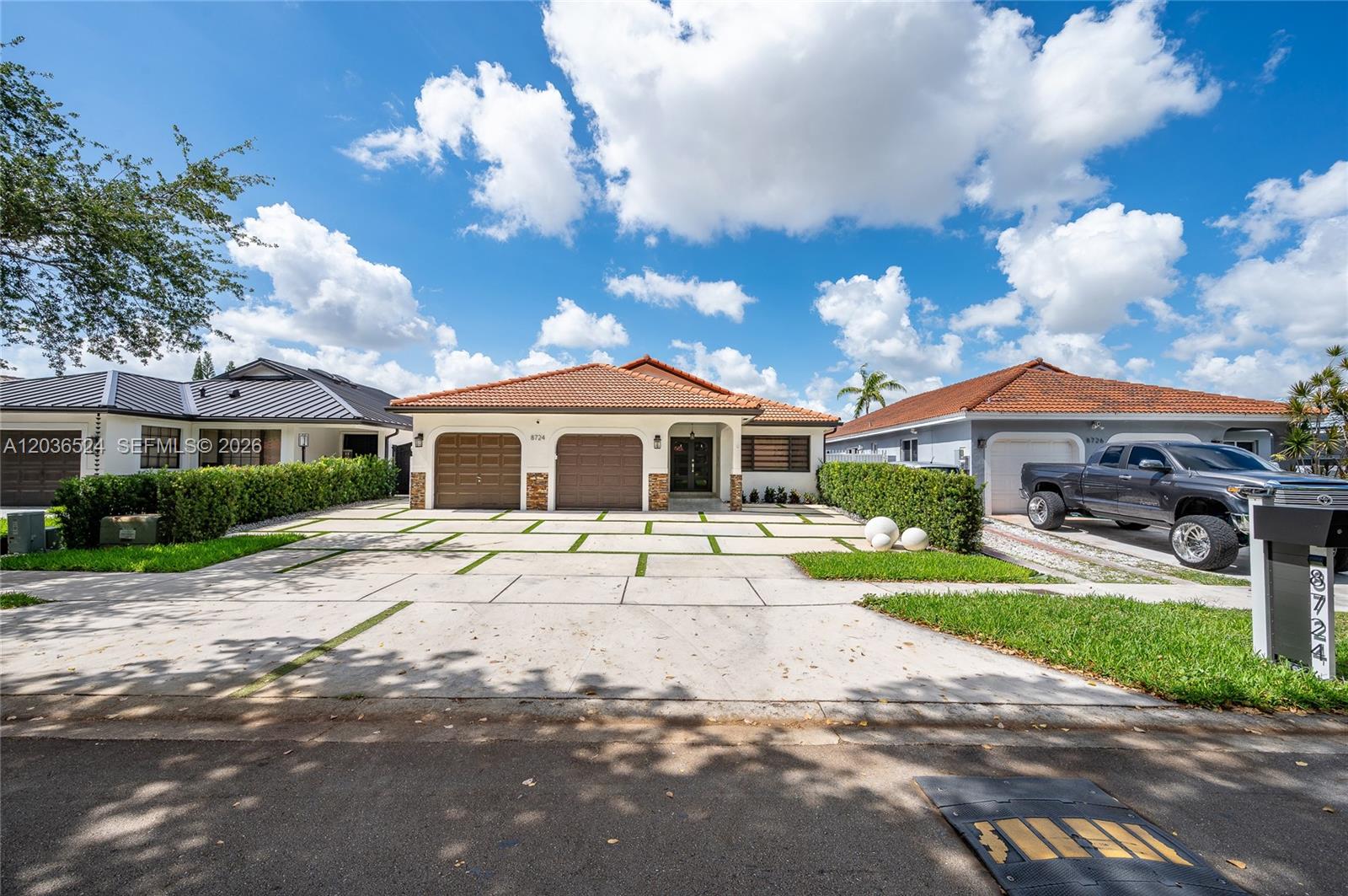 A single-story house with a two-car garage and a paved driveway featuring grass strips — 8724 NW 149th Ter, Miami Lakes FL 33018, MIAMI LAKES, FL