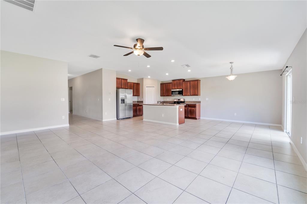 An open-concept kitchen and living area features light tile flooring, dark wood cabinets, and appliances — 10116 CARLOWAY HILLS DRIVE, WIMAUMA, FL