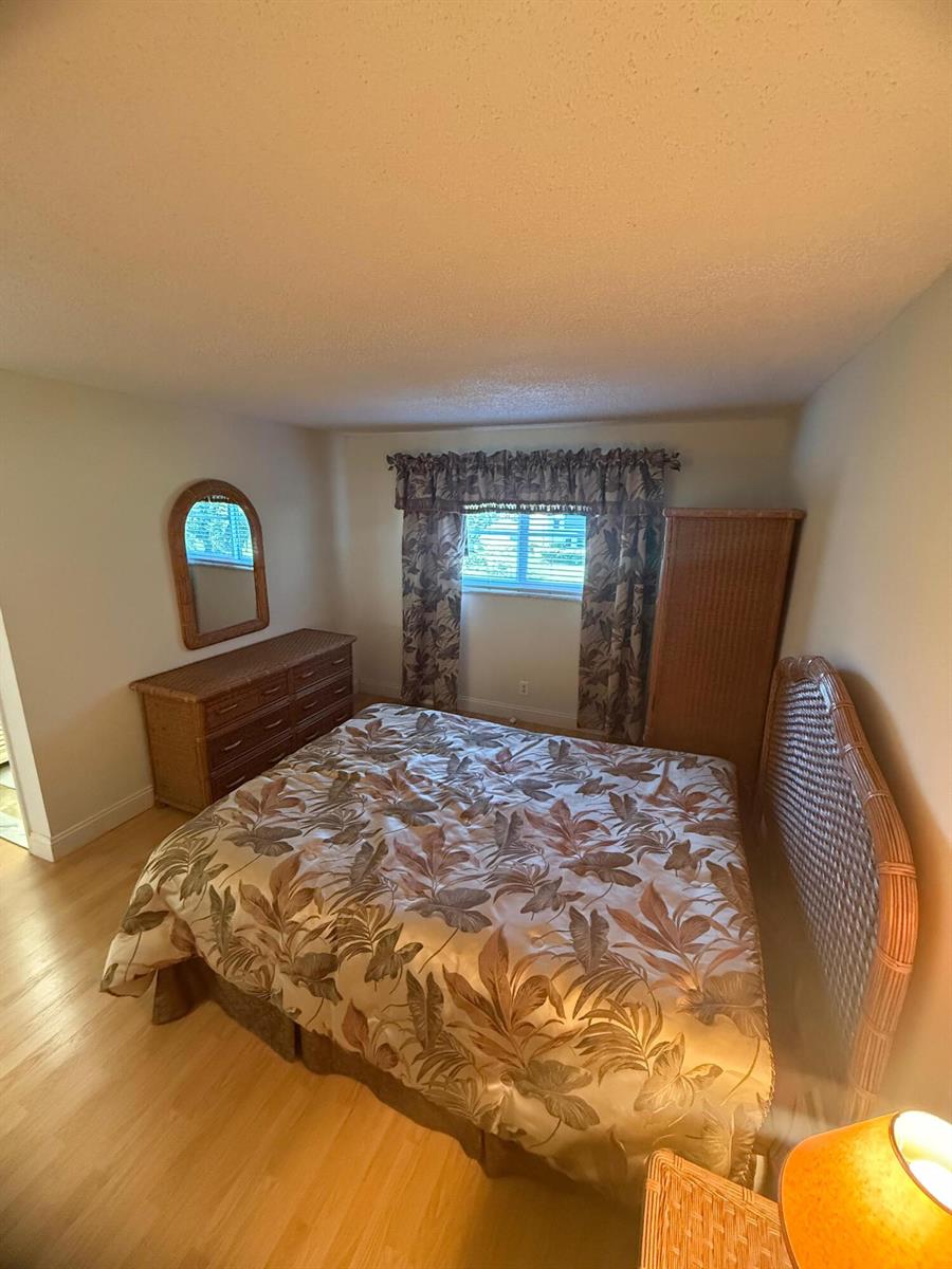 A bedroom features a wicker bed frame, matching dresser, and a botanical print comforter — 2601 NE 3rd Court # 202, Boynton Beach FL 33435, BOYNTON BEACH, FL