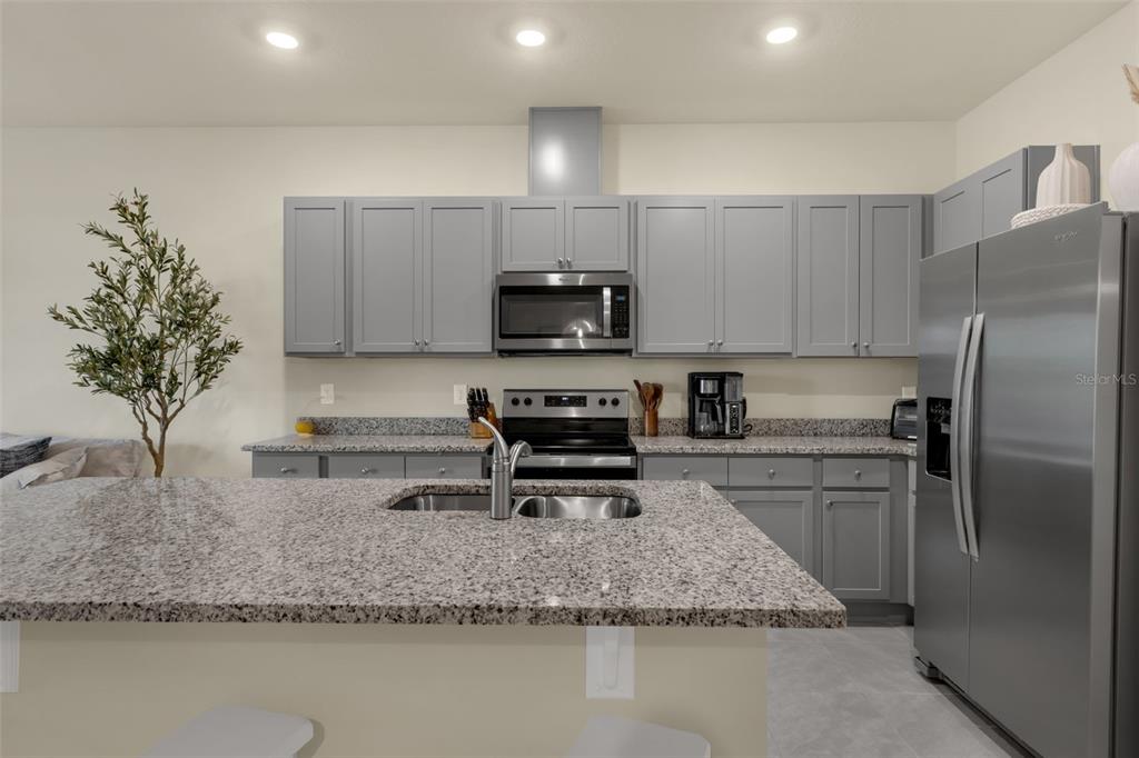 A kitchen features gray cabinets, granite countertops, stainless steel appliances, and a central island — 1219 LIDO DRIVE, HOWEY IN THE HILLS, FL