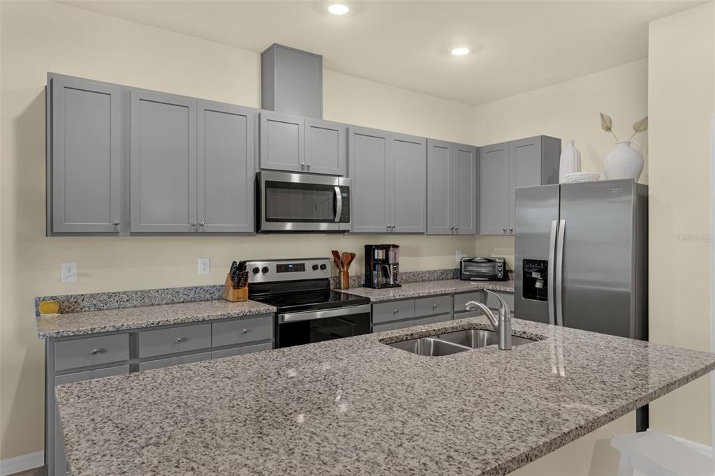 A kitchen features gray cabinets, granite countertops, stainless steel appliances, and a central island — 1219 LIDO DRIVE, HOWEY IN THE HILLS, FL