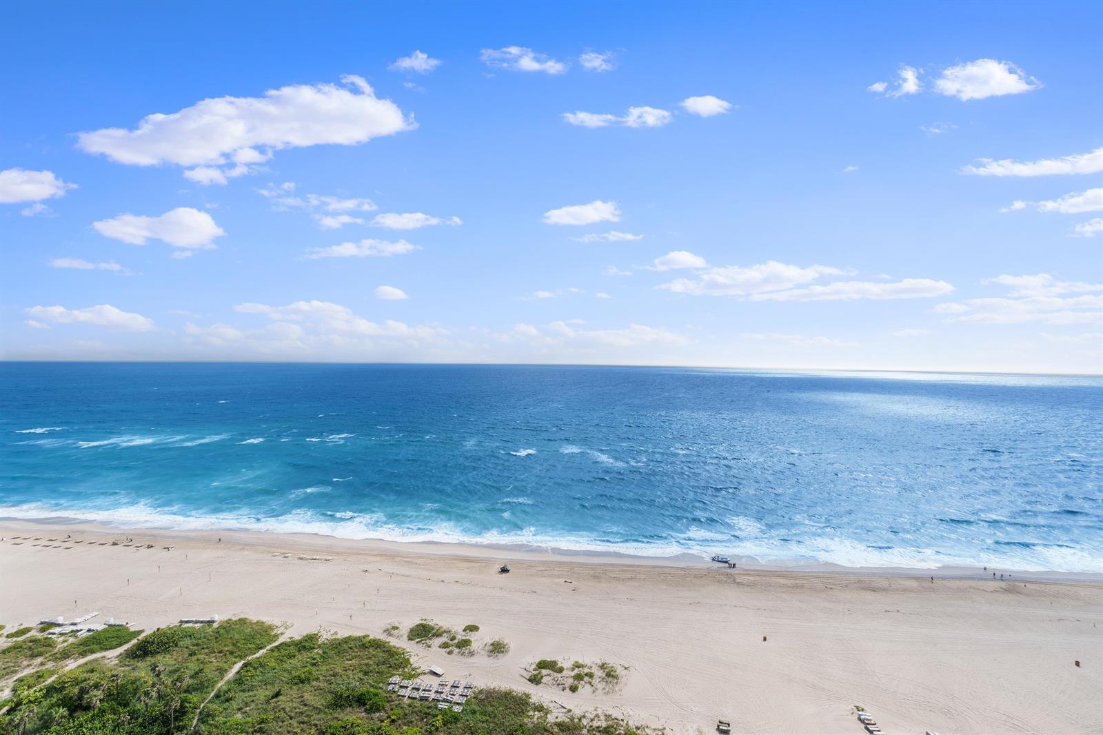 An elevated view of a sandy beach meeting the blue ocean under a cloudy sky — 3000 N Ocean Drive # 28e, Riviera Beach FL 33404, RIVIERA BEACH, FL