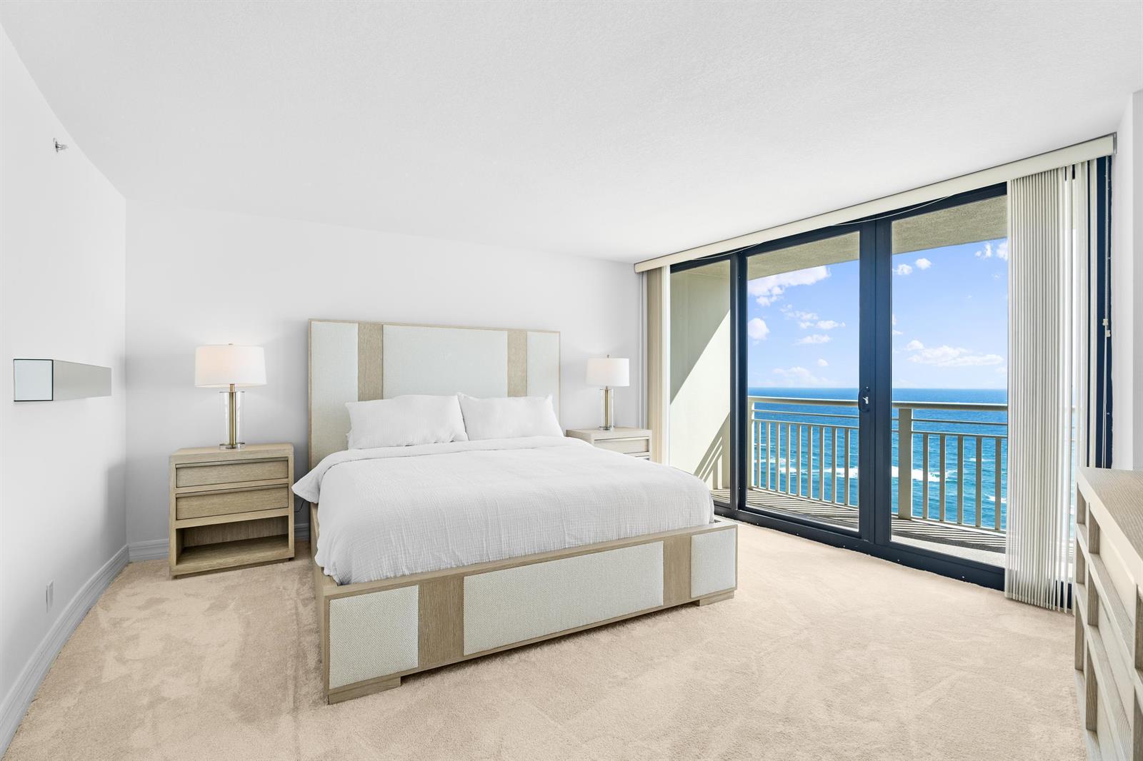 A bedroom features a bed, nightstands, and a large sliding glass door overlooking the ocean — 3000 N Ocean Drive # 28e, Riviera Beach FL 33404, RIVIERA BEACH, FL