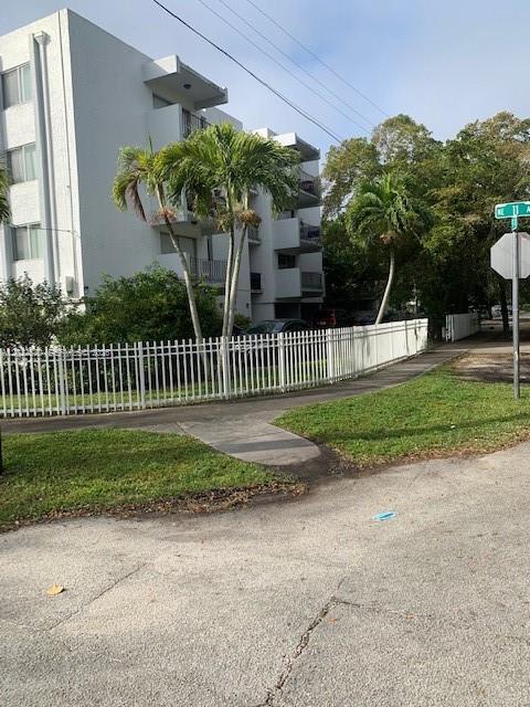 A white apartment building stands behind a white metal fence with palm trees in front — 1090 NE 129th St # 202, North Miami FL 33161, NORTH MIAMI, FL