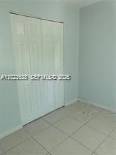 A room with light blue walls, white bi-fold closet doors, and light-colored tile flooring — 1090 NE 129th St # 202, North Miami FL 33161, NORTH MIAMI, FL