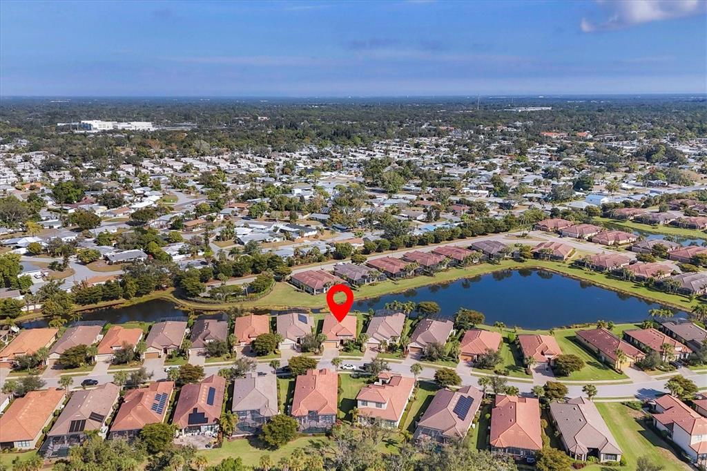An aerial view shows a residential neighborhood with houses surrounding a central lake — 2414 VACCARO DRIVE, SARASOTA, FL