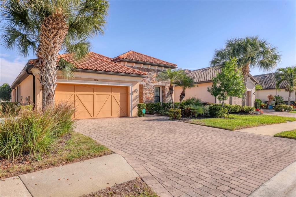A single-story house with a tiled roof, stone facade, and a paved driveway — 2414 VACCARO DRIVE, SARASOTA, FL