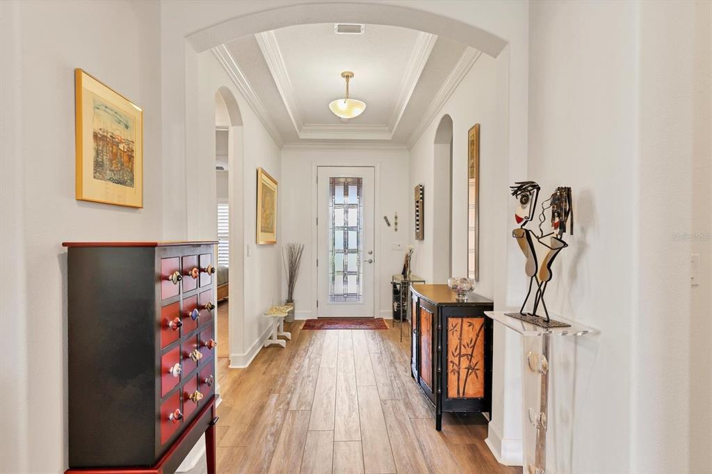 A bright entryway features wood-look tile flooring, a tray ceiling, and decorative furniture and art — 2414 VACCARO DRIVE, SARASOTA, FL