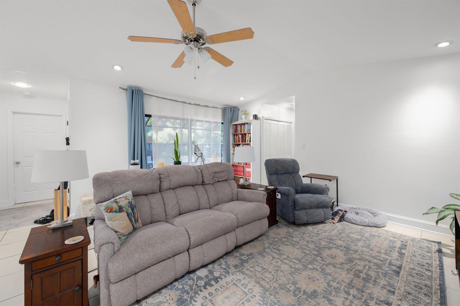 A living room features a gray sofa, a blue recliner, and a ceiling fan — 1433 Captains Walk # 18d, Fort Pierce FL 34950, FORT PIERCE, FL