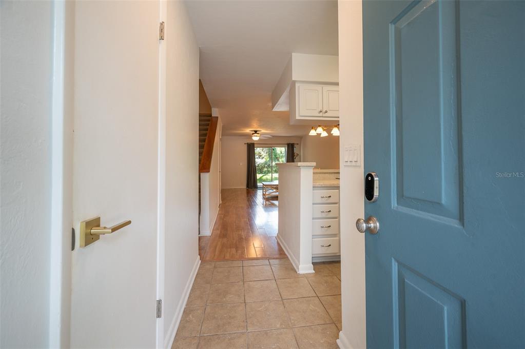 An entryway with tile flooring leads to a living area with wood floors and stairs — 4411 SW 34TH STREET UNIT 705, GAINESVILLE, FL