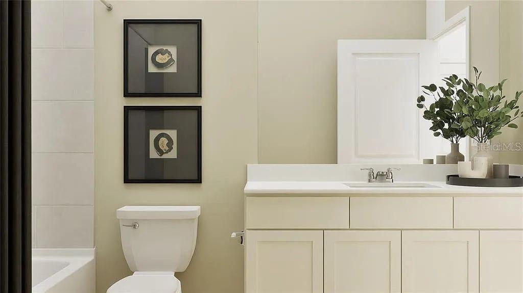 A bathroom features a white vanity, a toilet, and two framed wall art pieces — 5621 FIONA LANE, ST CLOUD, FL