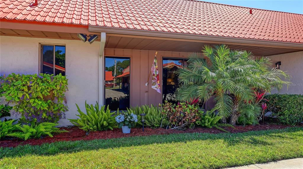 A single-story building exterior features a red tile roof, a covered porch, and landscaping — 6519 DRAW LANE UNIT 79, SARASOTA, FL