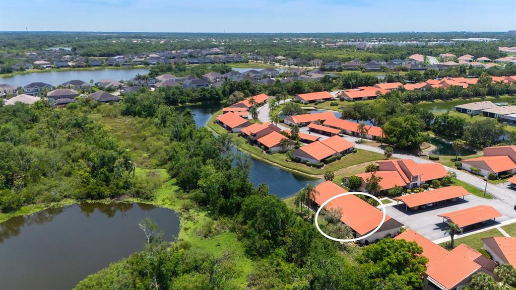 An aerial view shows a residential complex with orange-tiled roofs surrounded by ponds and trees — 6519 DRAW LANE UNIT 79, SARASOTA, FL