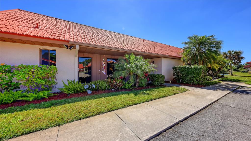 A single-story building with a red tile roof, beige exterior, and landscaped front yard — 6519 DRAW LANE UNIT 79, SARASOTA, FL