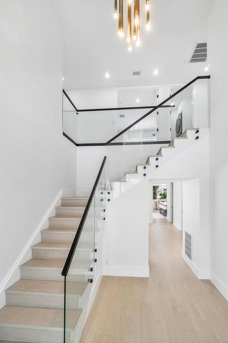 A modern staircase with light wood steps and a glass railing leads to a landing — 5768 NW 39th Avenue, Boca Raton FL 33496, BOCA RATON, FL