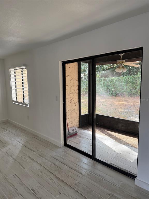 A room with light-colored tile flooring, a window with blinds, and a sliding glass door — 2611 PINE LAKE TERRACE UNIT A, SARASOTA, FL