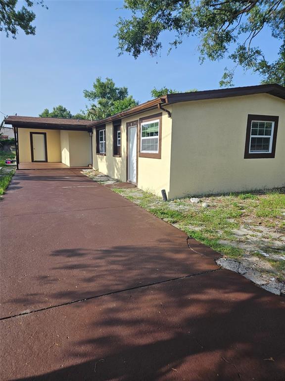 A yellow single-story house with a brown roof and a long, painted red driveway — 3810 E 32ND AVENUE, TAMPA, FL