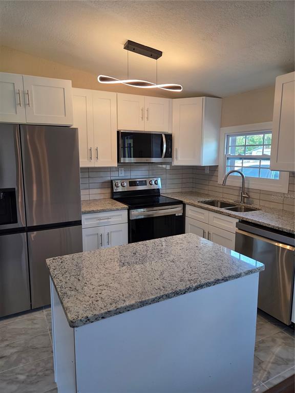 A kitchen features white cabinets, granite countertops, stainless steel appliances, and a central island — 3810 E 32ND AVENUE, TAMPA, FL