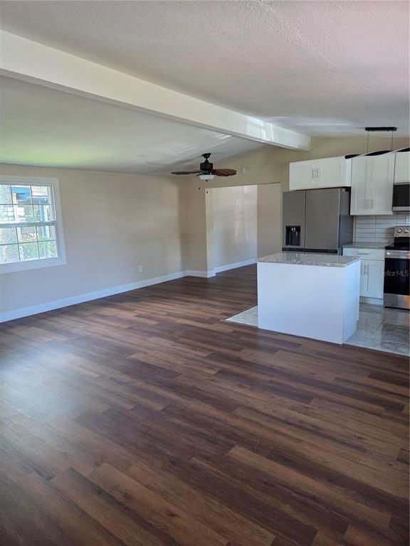 An open-concept living area features wood-look flooring, a ceiling fan, and a kitchen with white cabinets — 3810 E 32ND AVENUE, TAMPA, FL
